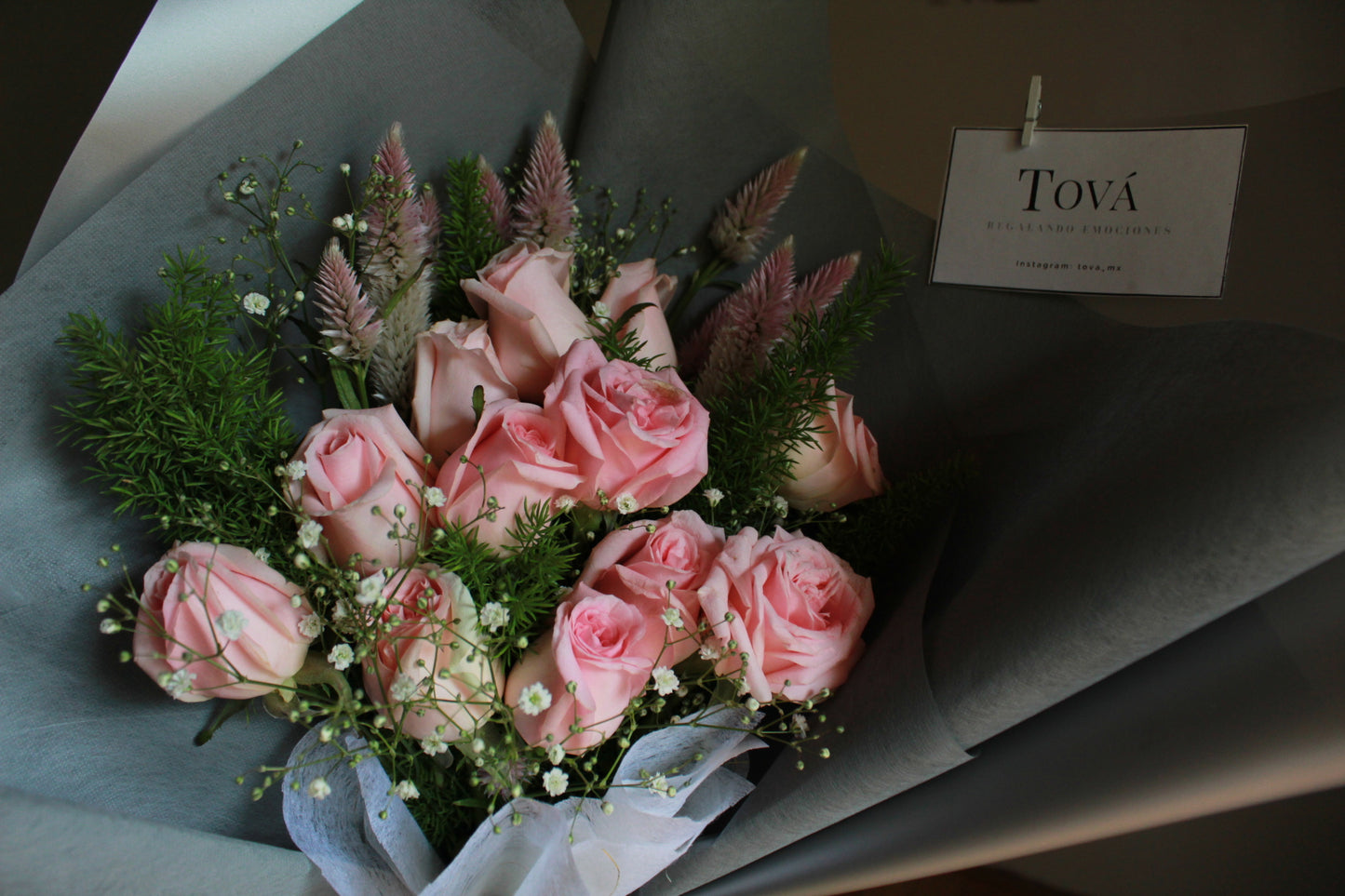 Docena de rosas de invernadero con follaje.
