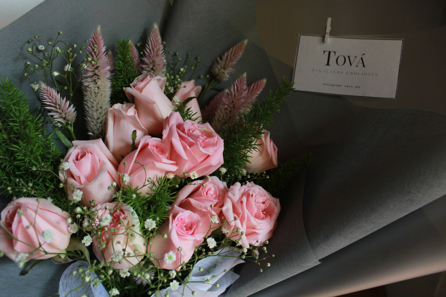 Docena de rosas de invernadero con follaje.