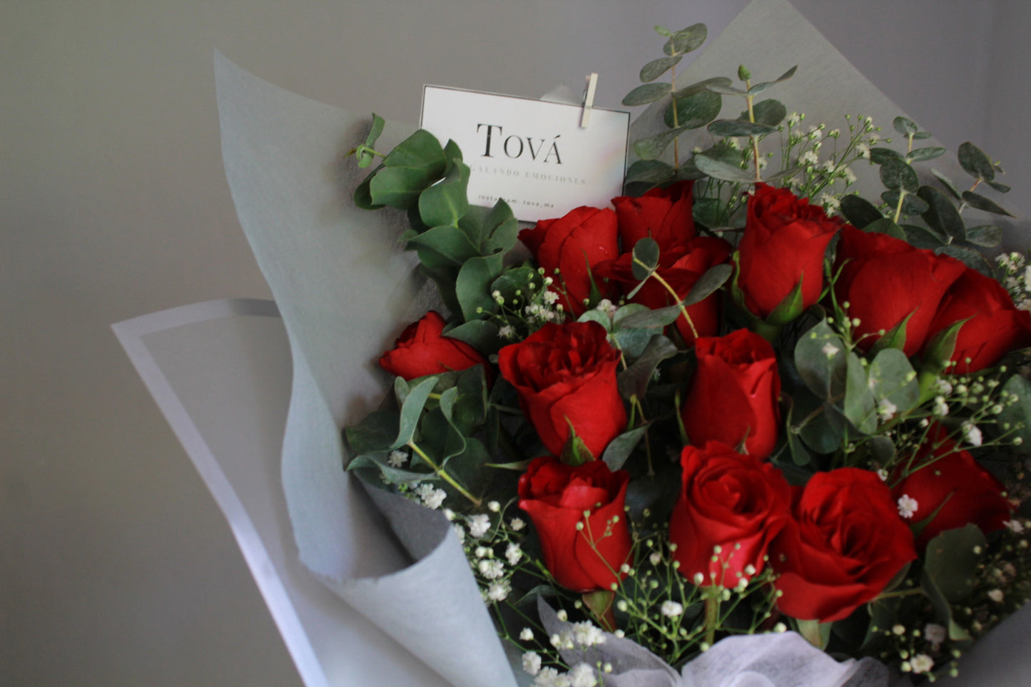 Docena de rosas de invernadero con follaje.