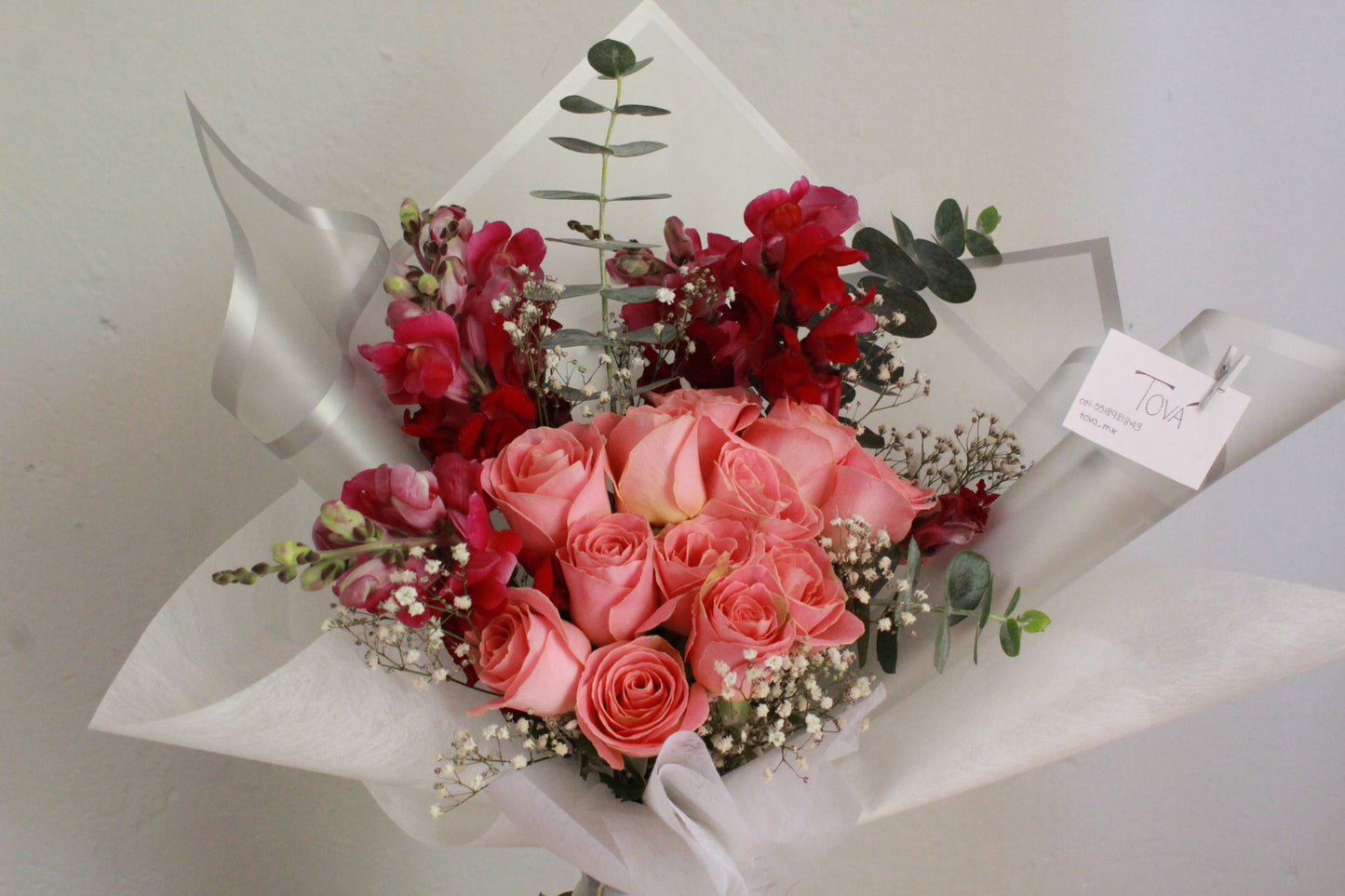 Docena de rosas de invernadero con perritos y follaje.