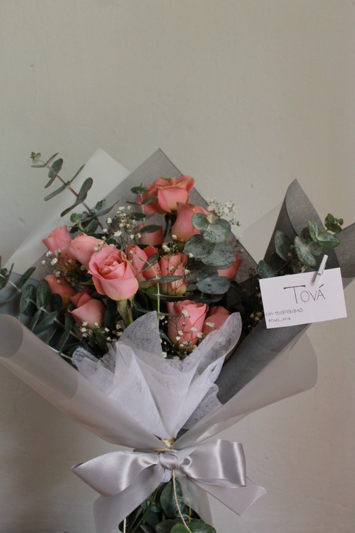 Docena de rosas de invernadero con follaje.