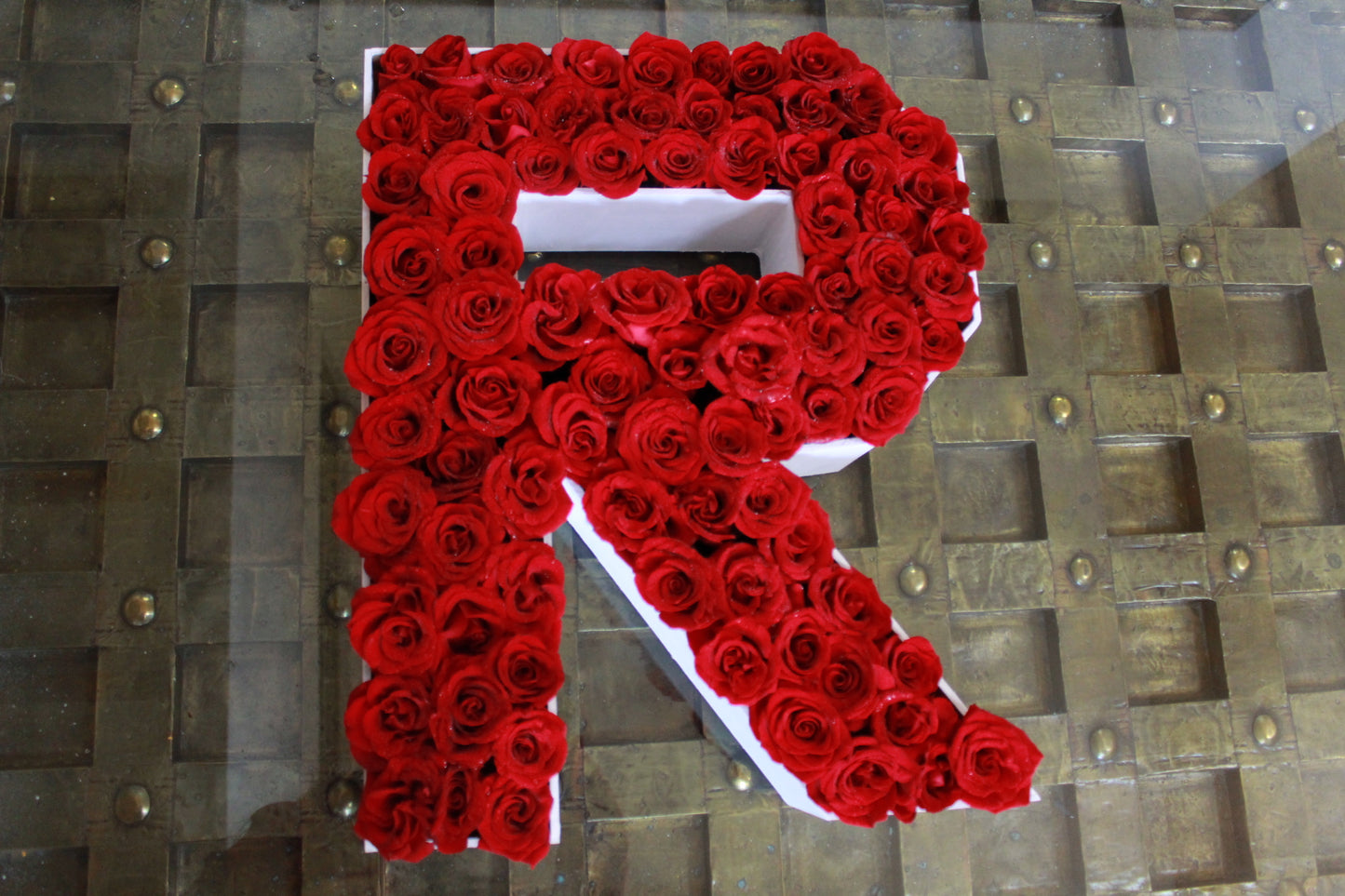 Letras con aproximadamente 100 rosas sobre caja de madera.