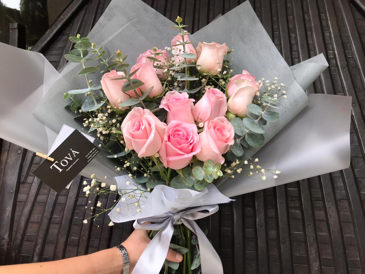 Docena de rosas de invernadero con follaje.