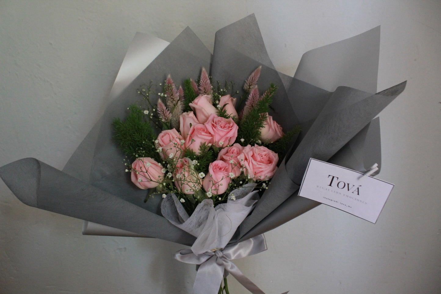 Docena de rosas de invernadero con follaje.