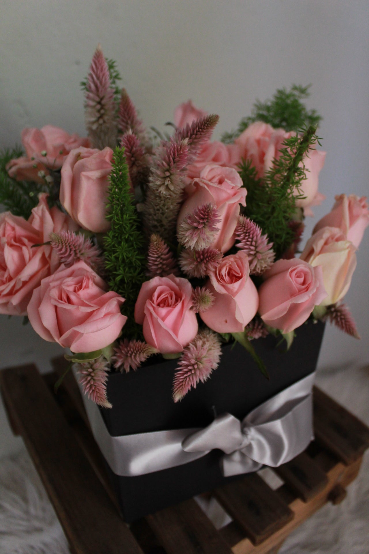 Caja de madera hecha y pintada a mano, con una docena de rosas y follaje.