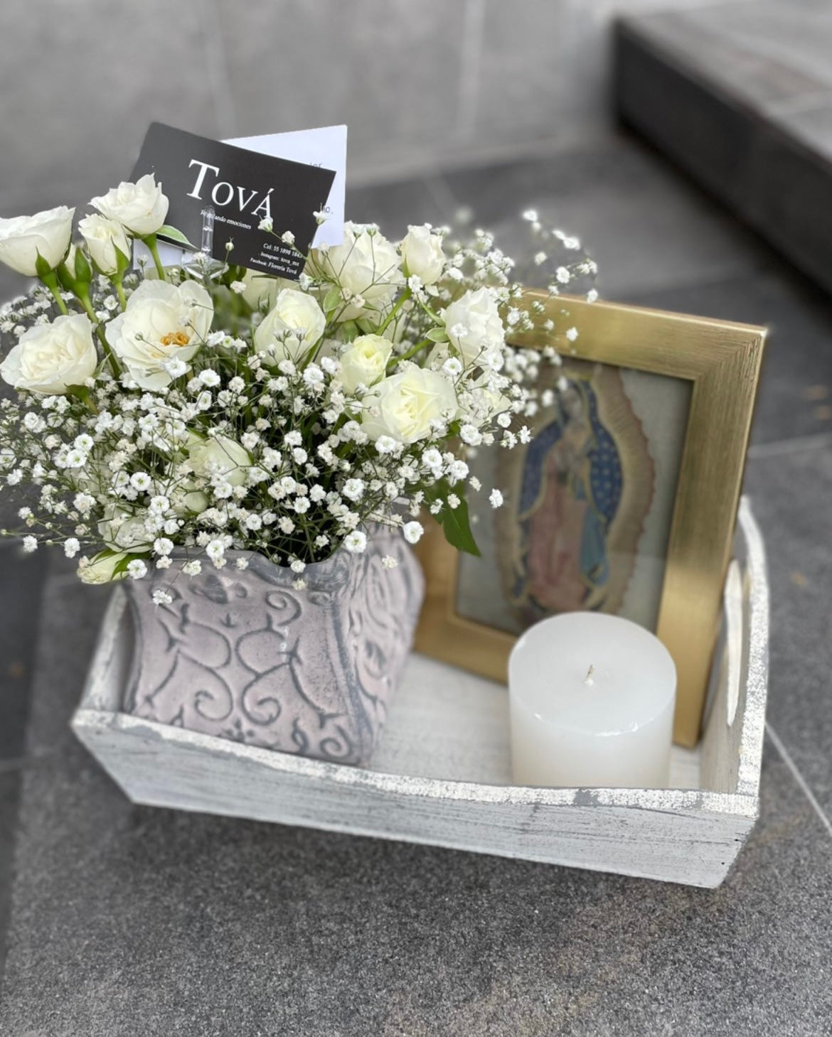 Paquete que incluye arreglo de flores en base de cerámica, portaretratos y una vela.