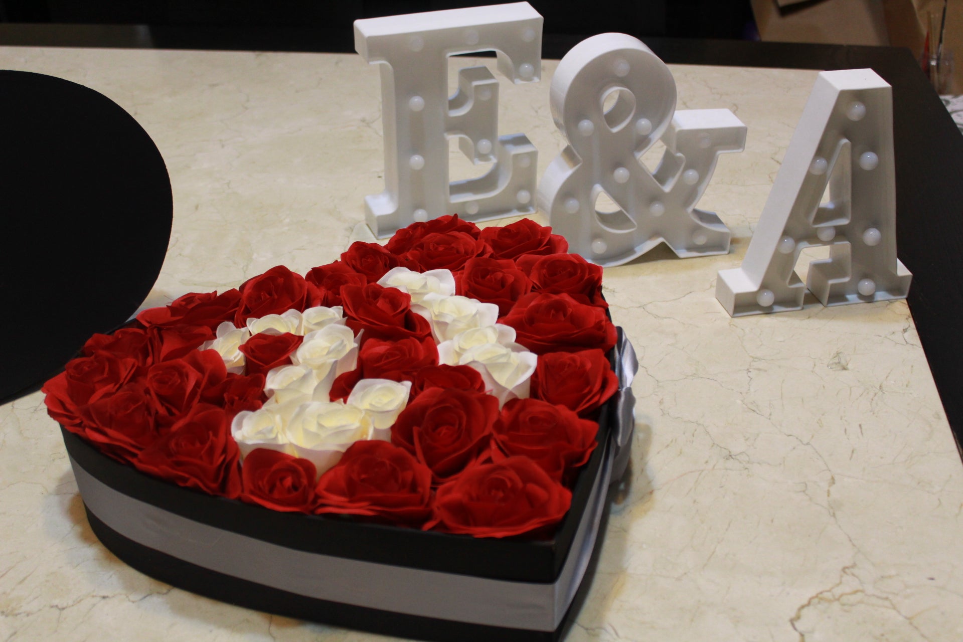Corazón con rosas artificiales sobre caja de madera.