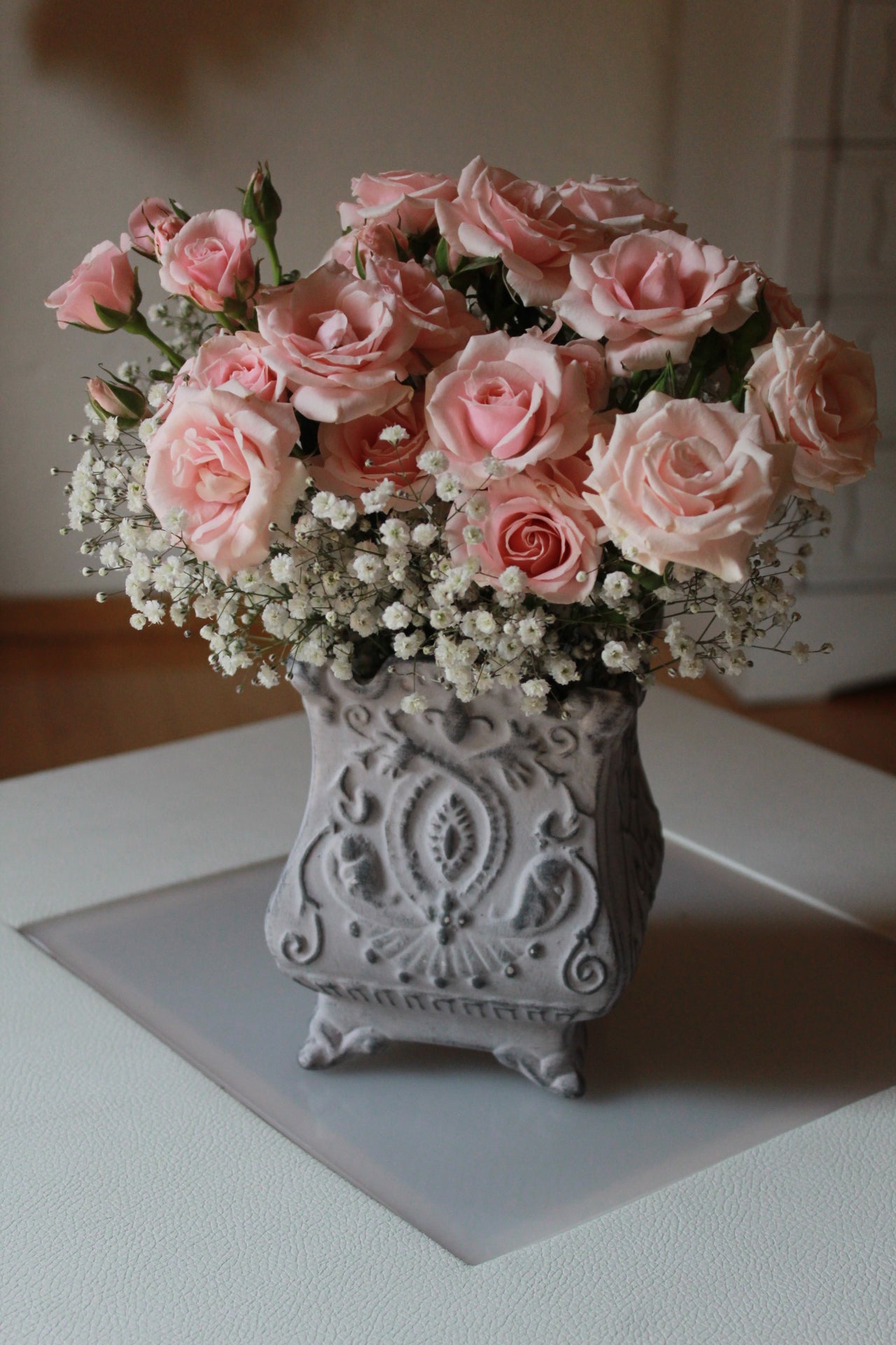 Mini rosa con follaje sobre florero de cerámica.
