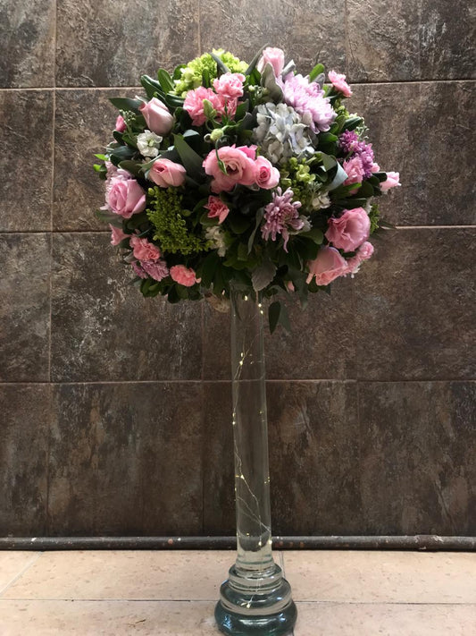 Lisianthus, rosas, hortensias y follaje; sobre base de vidrio con agua e iluminación.