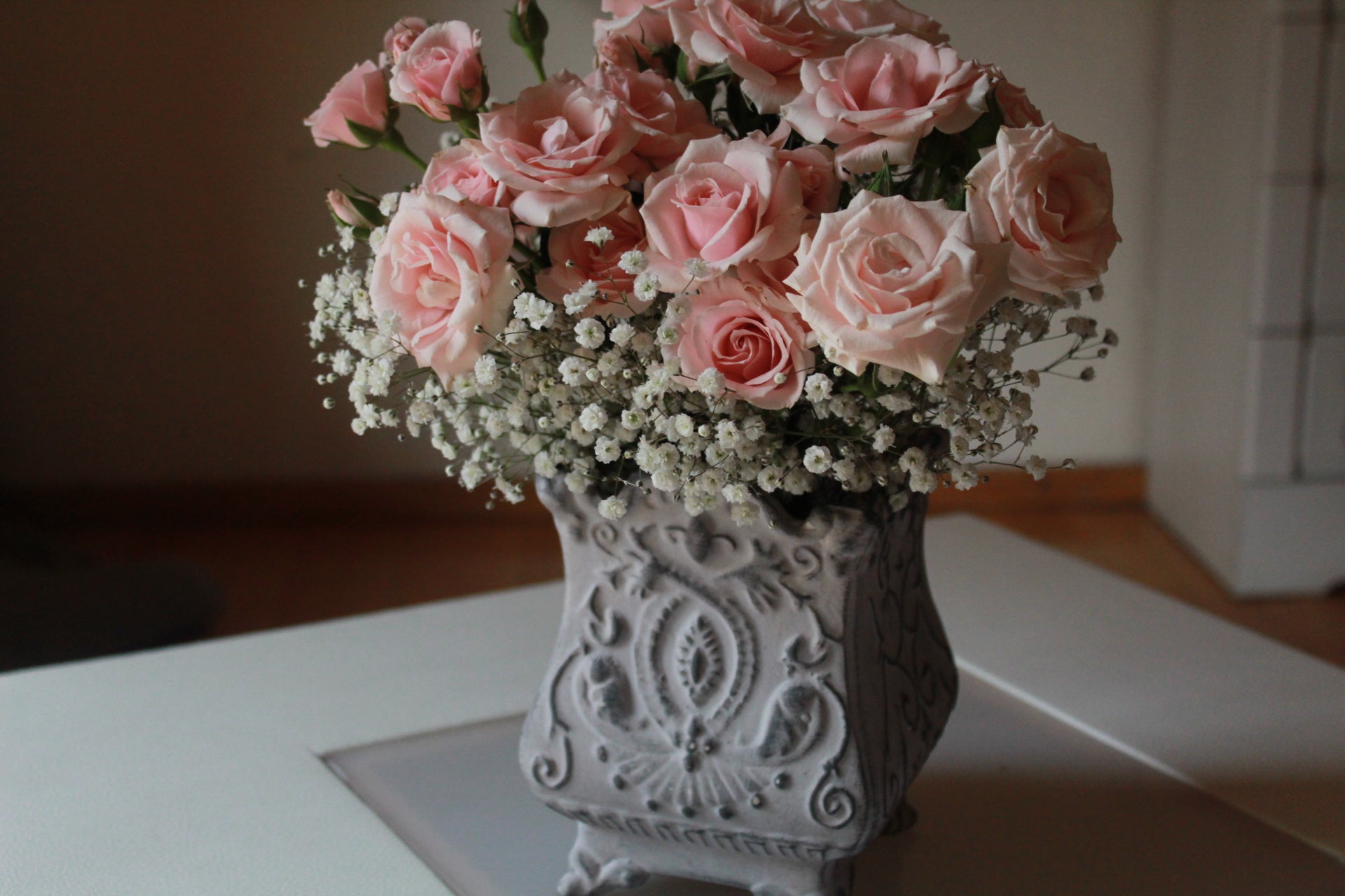 Mini rosa con follaje sobre florero de cerámica.