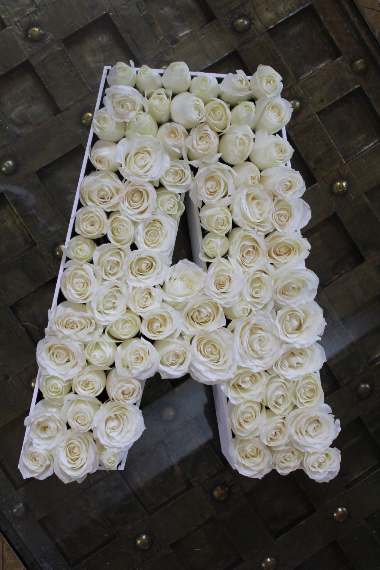 Letras con aproximadamente 100 rosas sobre caja de madera.
